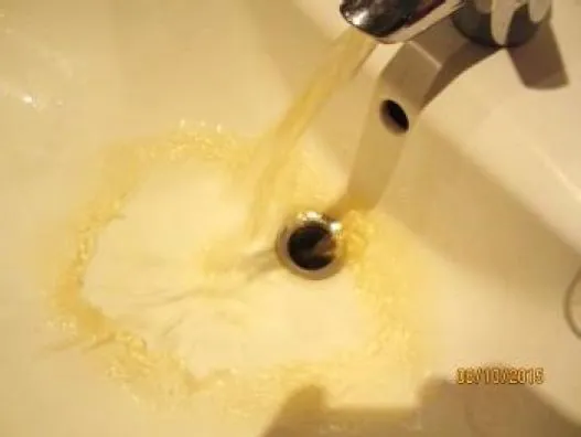 Waschbecken, in das braun gefärbtes Wasser aus der Armatur läuft